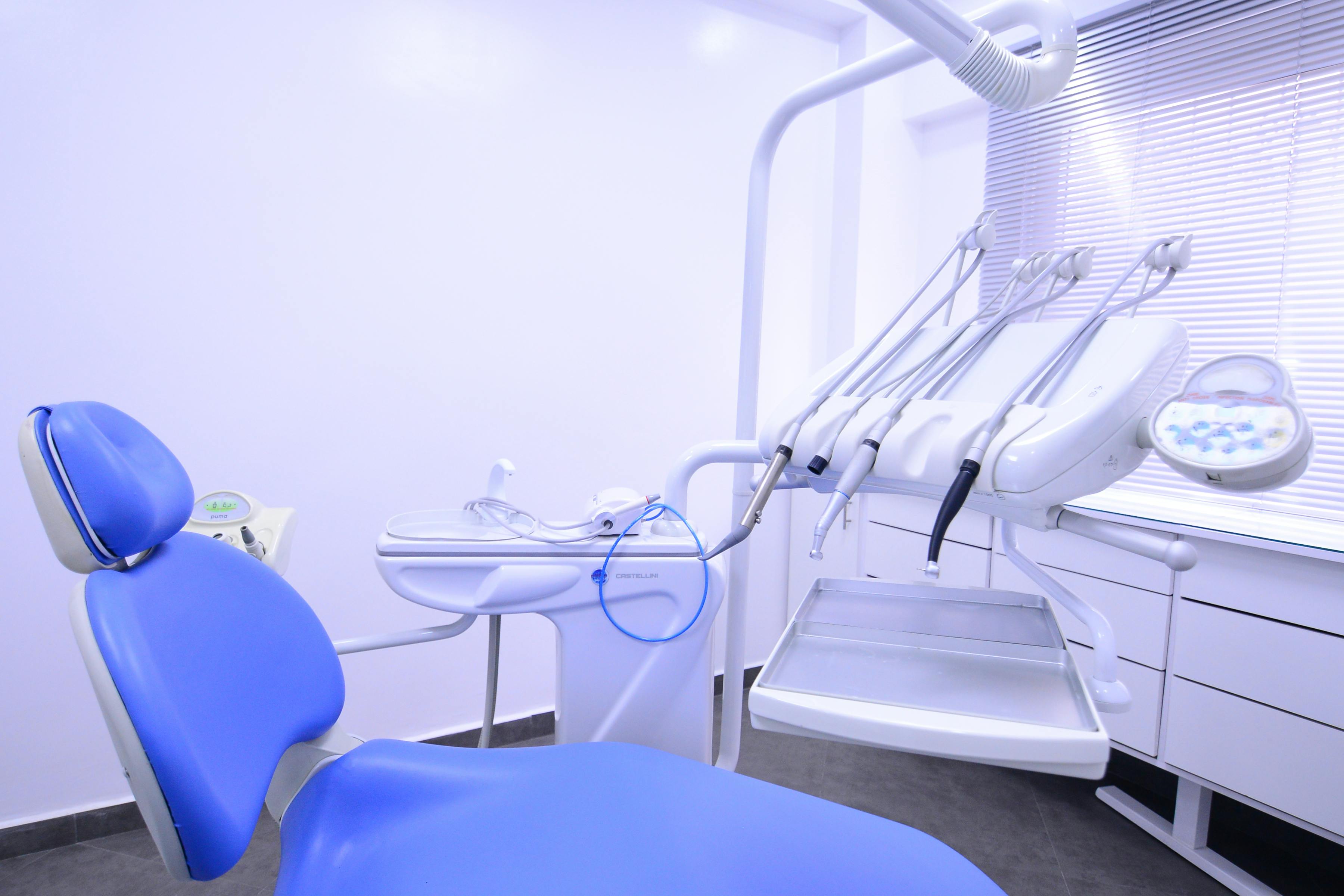 white dental chair with modern equipment placed in spacious office with cabinets and various tools in contemporary dentistry with glass wall