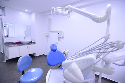 White dental chair with modern equipment placed in spacious office with cabinets and various tools in contemporary dentistry with glass wall