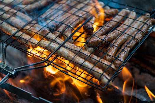 Juicy sausages being grilled over an open flame, capturing the essence of outdoor cooking.