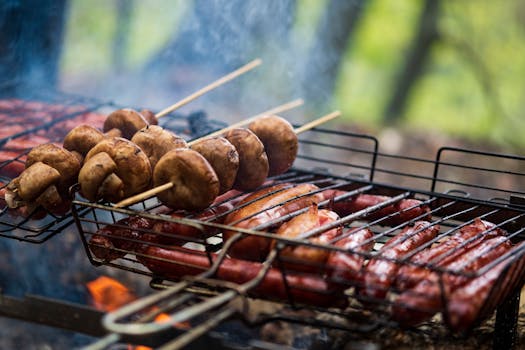Delicious skewered mushrooms and sausages grilling over charcoal on a barbecue grill outdoors.