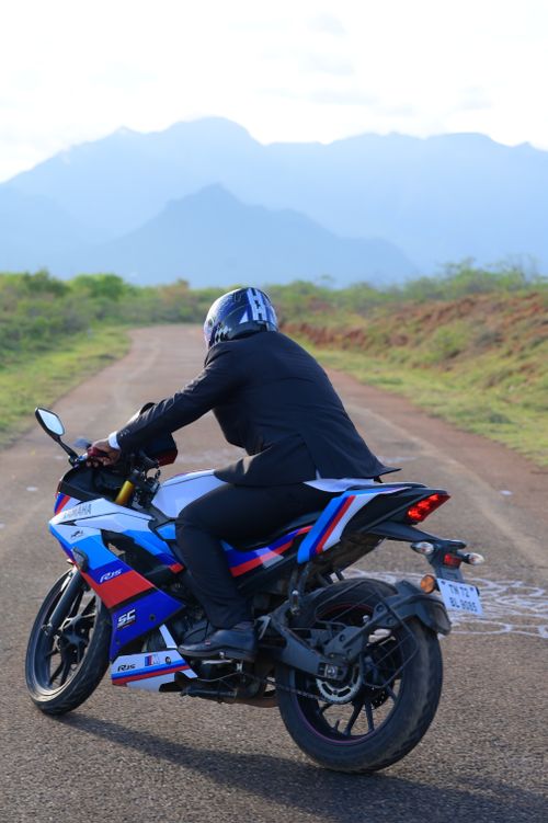 Free Man in a suit riding a motorcycle on a rural road with mountain views. Stock Photo