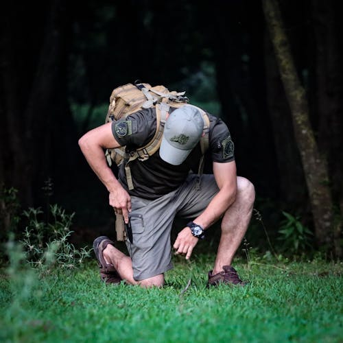 Man with Backpack Crouching in Forest