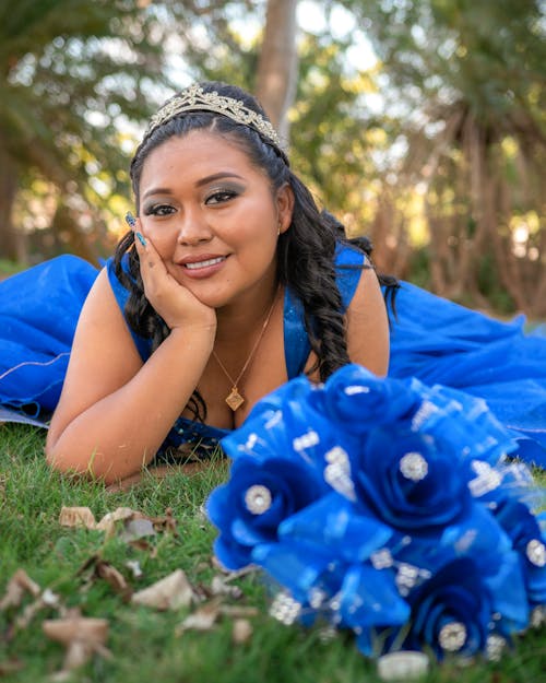 Free Woman in Blue Dress Lying Down with Flowers Stock Photo