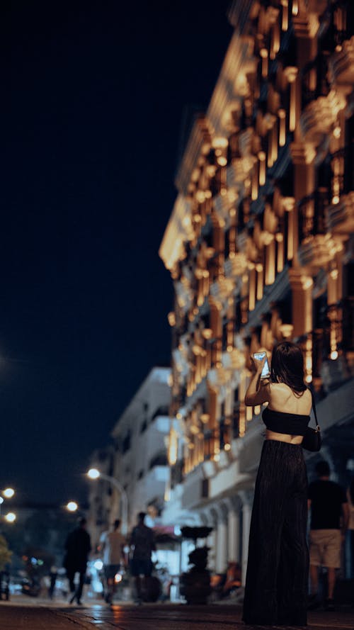 Back View of Woman in Black Dress in City at Night
