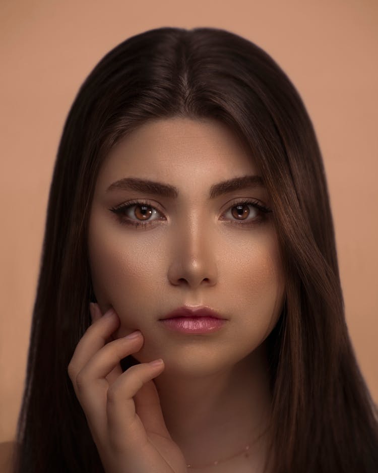 Portrait Of Woman With Brown Eyes Touching Her Face With Hand