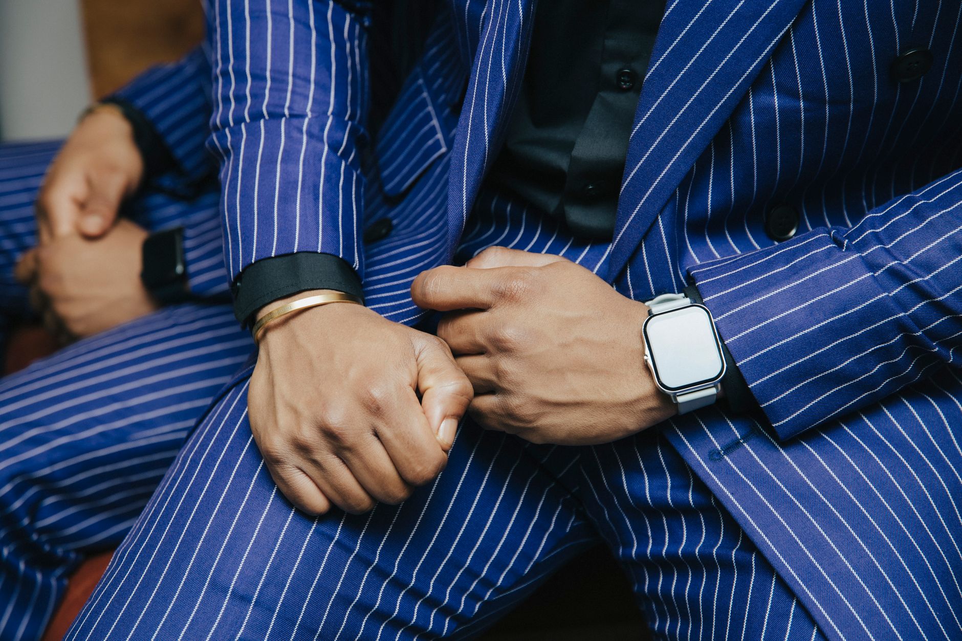 Close-up of men in blue pinstriped suits with wristwatches, showcasing elegance and fashion sense.
