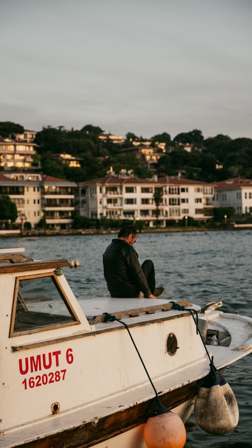 Man Sitting on a Deck of his Fishing Boat in Sea Harbor, Istanbul, Turkey