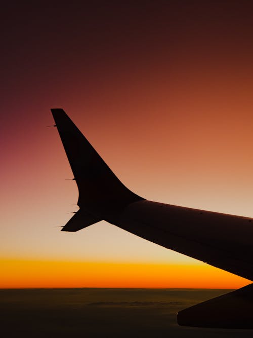 Silhouetted Airplane Wing on the Background of a Sunset 