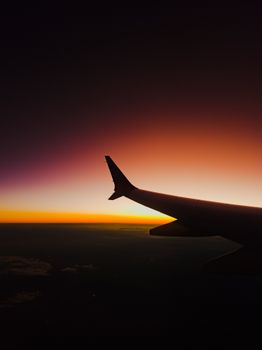 A stunning silhouette of an airplane wing against a vibrant sunset sky. Perfect for travel or aviation themes.