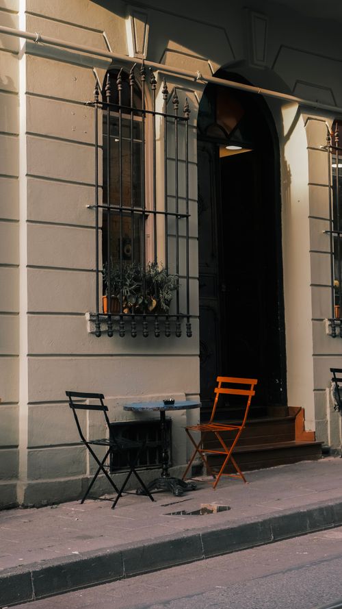 Free Cozy outdoor café setting with chairs and table outside a traditional building entrance. Stock Photo