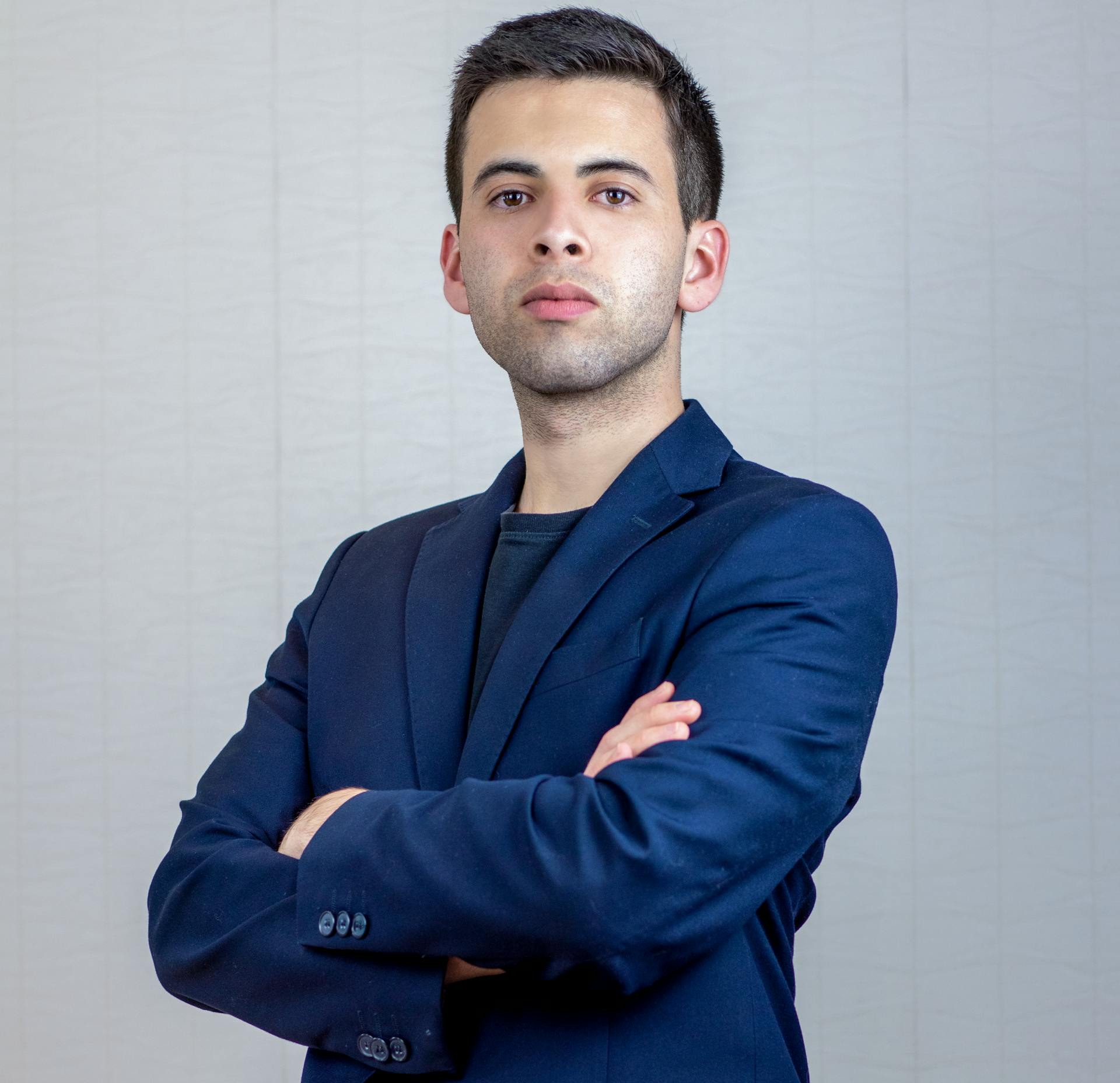 Portrait of a confident businessman in a blue suit with arms crossed, showcasing professionalism.