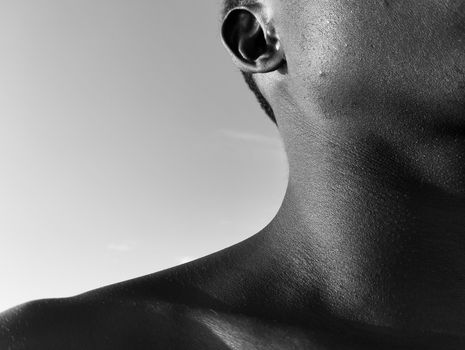 Monochrome close-up of a shirtless man's ear and neck, emphasizing texture and form.
