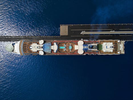 Top view of a luxury cruise ship with pool docked at a pier in the ocean.