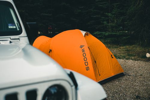 Free Orange tent set up by a white vehicle in Jasper, AB, Canada forest. Stock Photo
