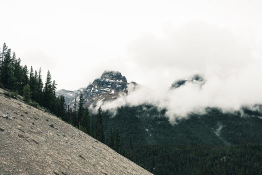 Snow-covered mountain peaks shrouded in mist and clouds in Jasper National Park, Alberta, Canada.