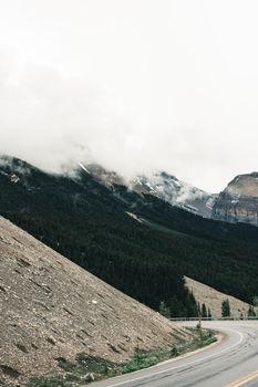 Curved road winding through misty mountains in Jasper National Park, Alberta, Canada.