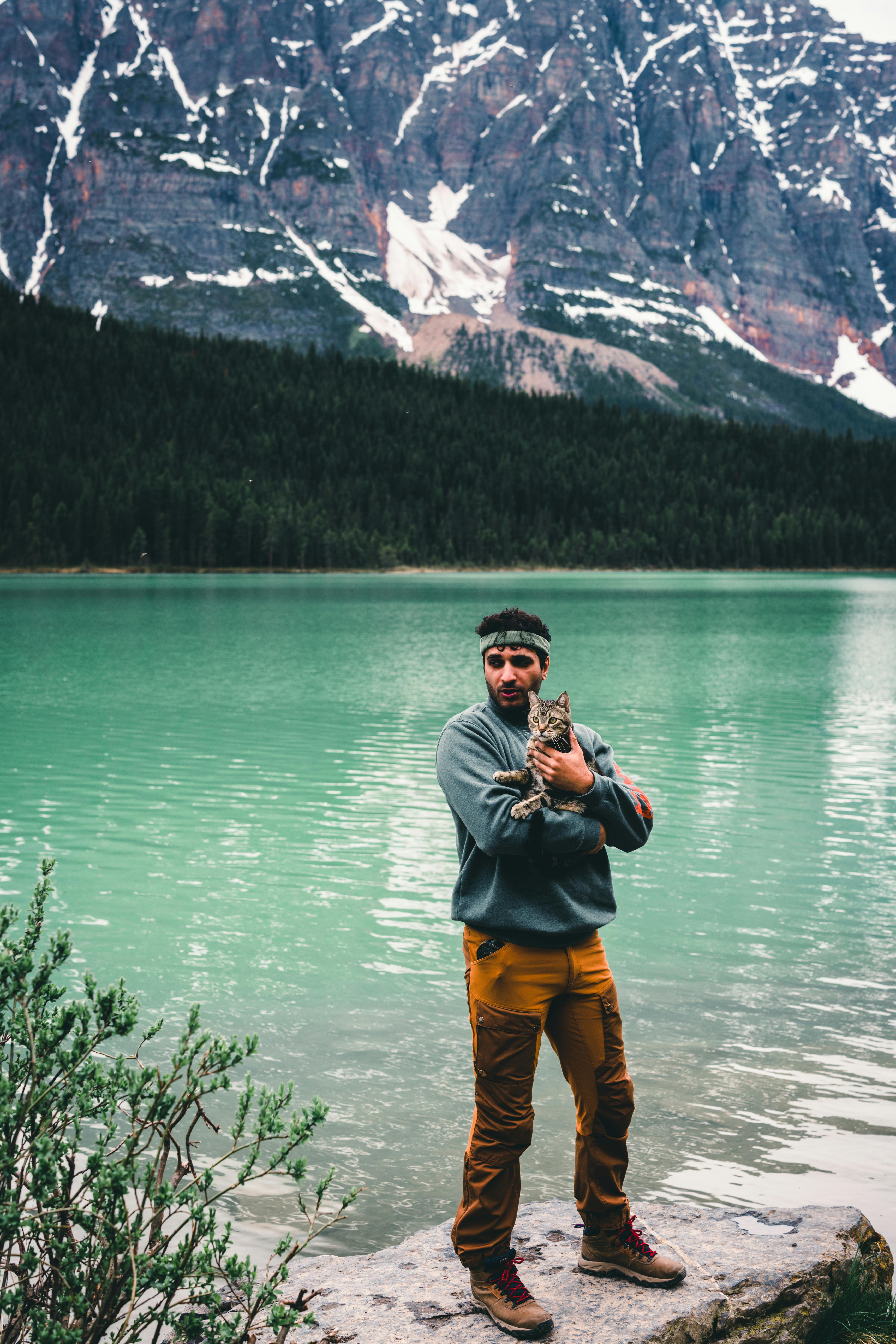 A man standing in front of a lake with a dog