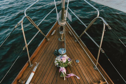 Buquê De Flores Brancas E Roxas Em Um Barco De Madeira Marrom No Solo Em Um Corpo D'água