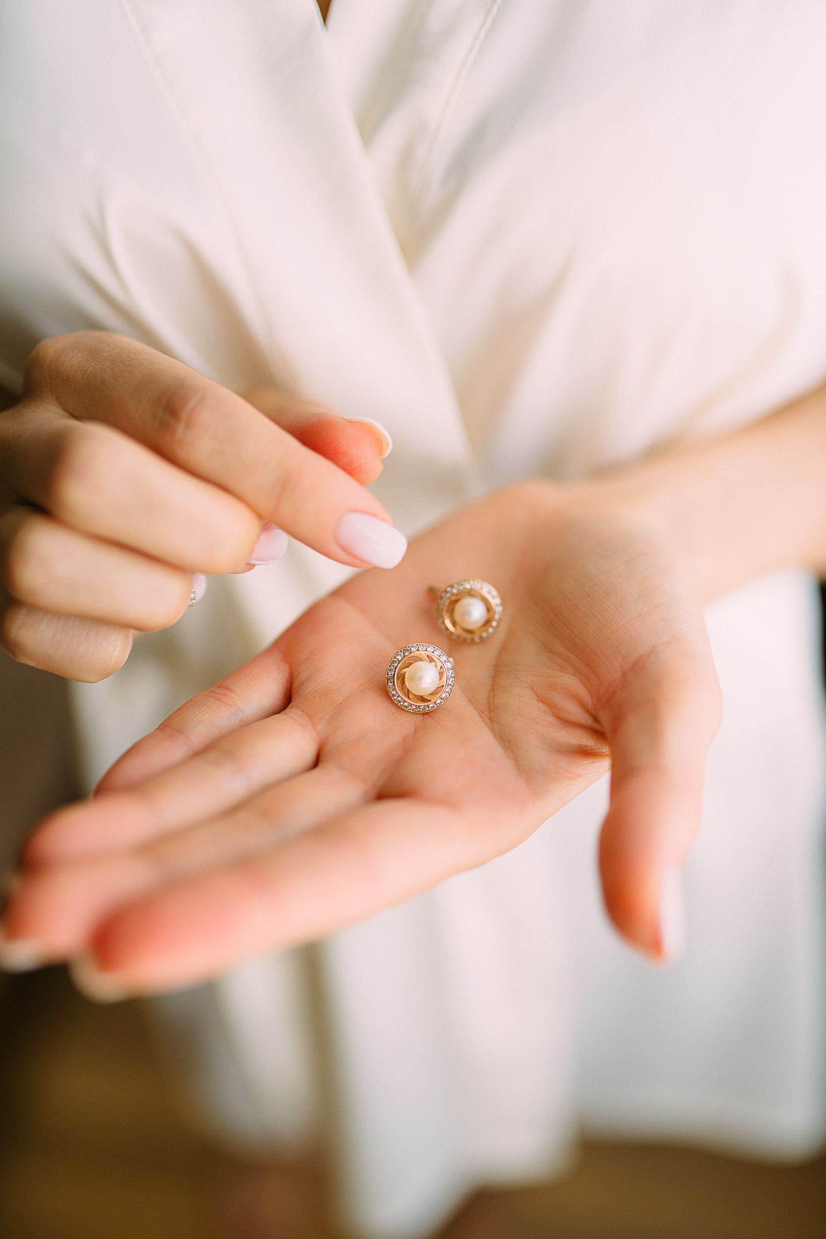 A hand wearing a diamond ring resting on linen