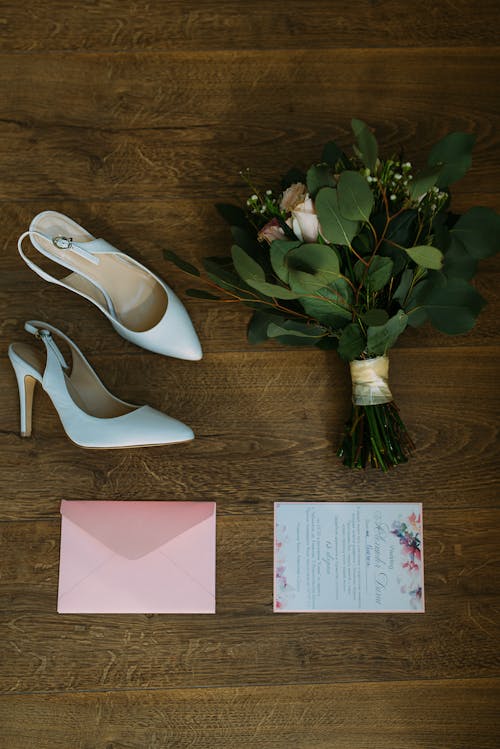 Pair Of White Leather Pointed-toe Slingback Shoes Beside Bouquet Of Flowers