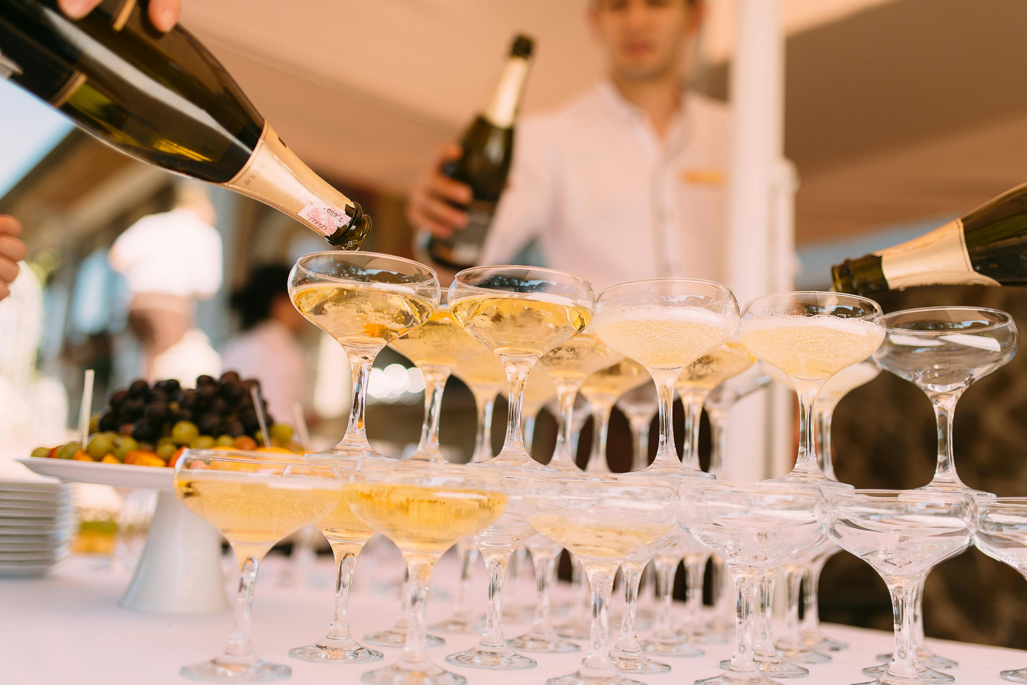 person pouring liquor in cocktail glasses