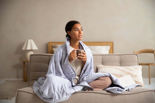 Woman Wearing a Bathrobe Sitting in Bed and Drinking Coffee 