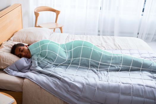 Relaxing scene of a woman peacefully sleeping under a cozy weighted blanket in a serene bedroom.