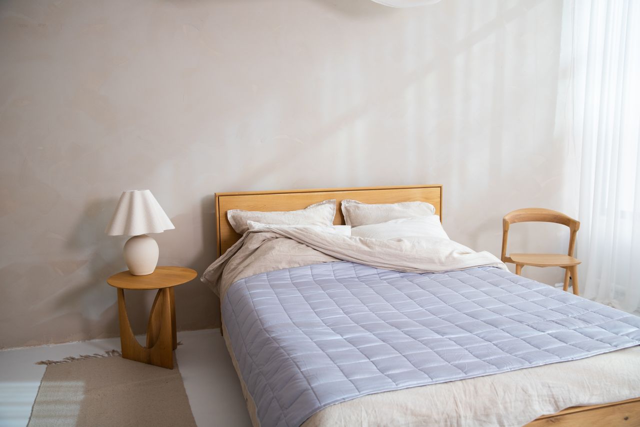 Blue throw blanket layered on a bed with wooden headboard