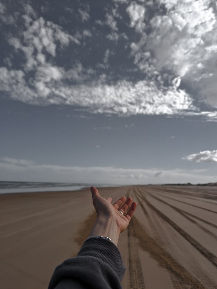 A Person With Their Hand Reached Out On The Beach 