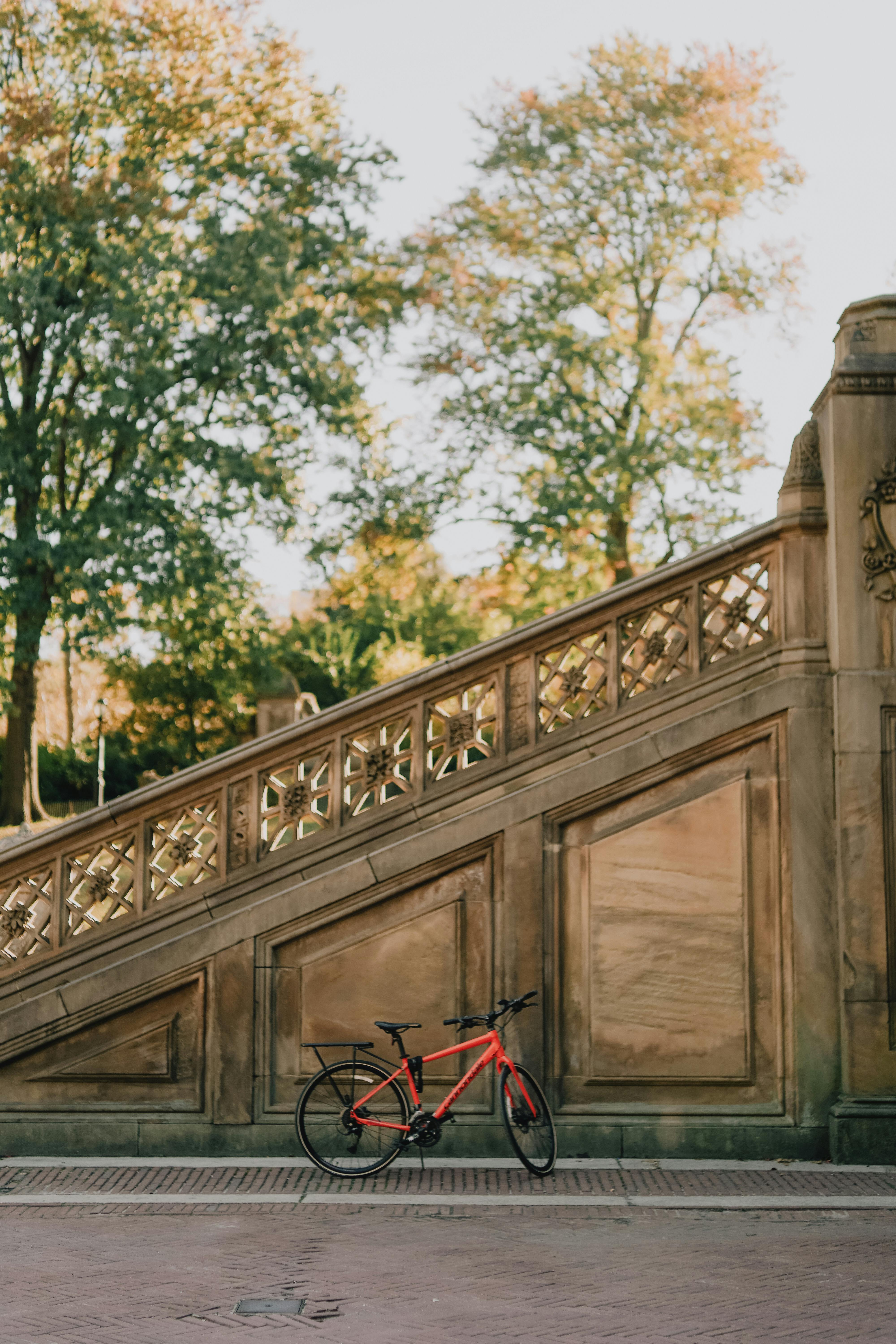 Red bicycle leaning on historic stone staircase in Central Park, New York City.