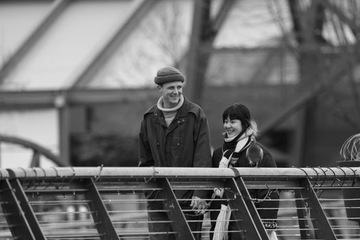 A joyful couple holding hands while walking on a bridge in Vancouver.