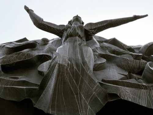 Free Low angle view of an intricate sculpture with dramatic outstretched arms, emphasizing art and structure. Stock Photo