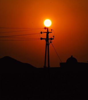 A captivating silhouette of electric poles against a red sunset sky in Sakri, Maharashtra.