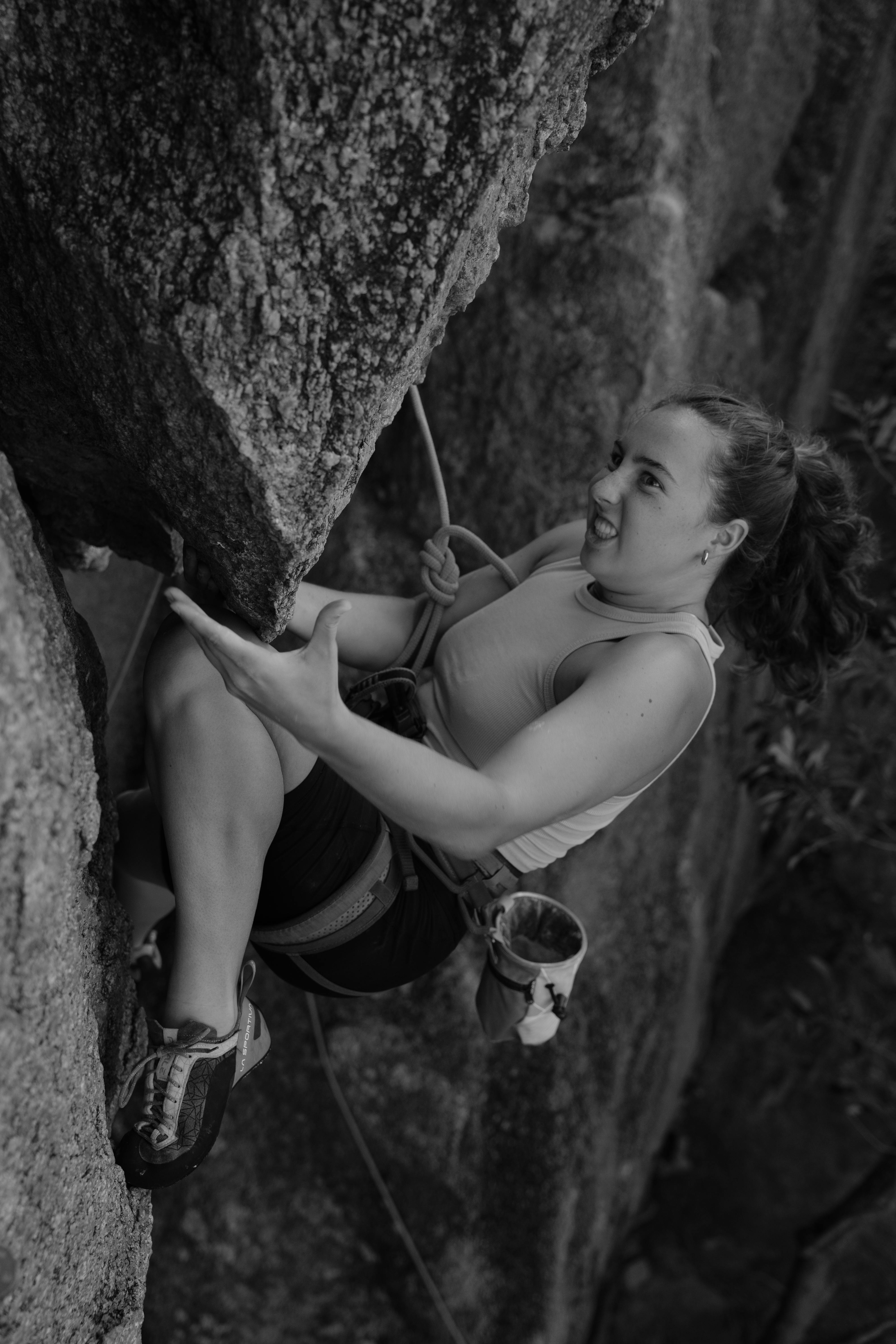 A determined female rock climber ascending a steep cliff in Ko Tao, Thailand.