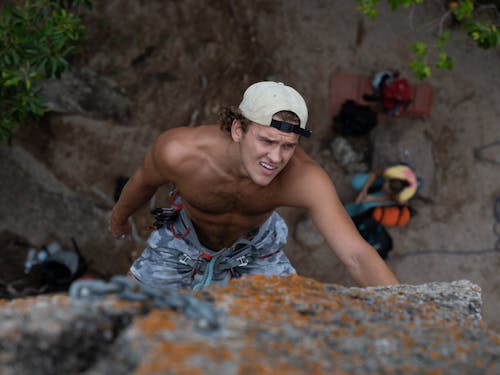 Shirtless Man Climbing a Rock