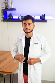 Portrait of a male medical professional standing indoors wearing a white coat.
