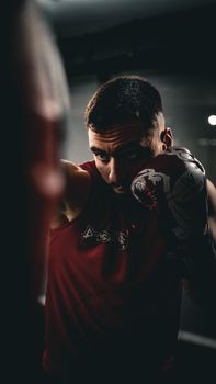 Focused male boxer practicing punches indoors with boxing gloves, showcasing sports determination.
