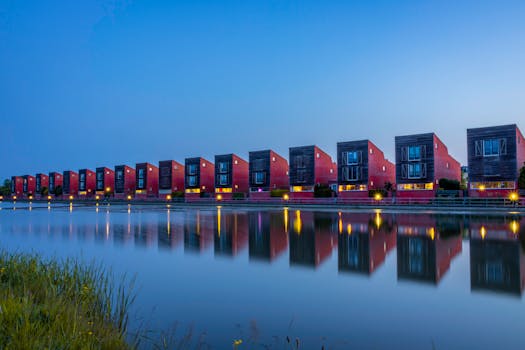 Row of modern red brick houses reflecting in a calm canal in Groningen, Netherlands, during twilight.