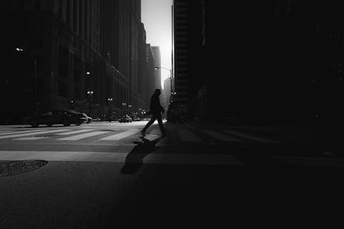 Grayscale Photo of Person Walking on Road