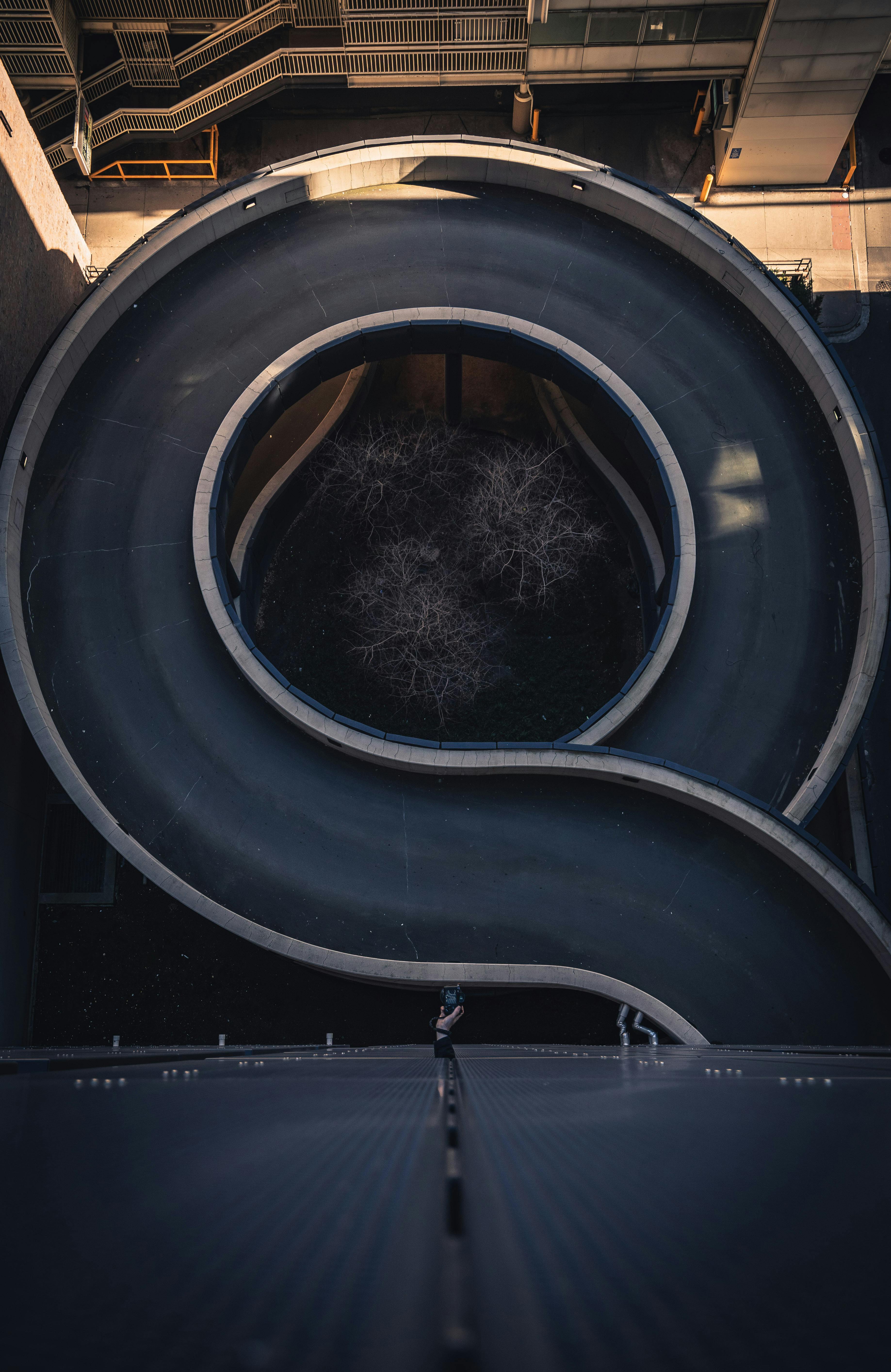 一张航拍照片中，现代螺旋坡道结构矗立于城市环境，其间有一个孤独的人物