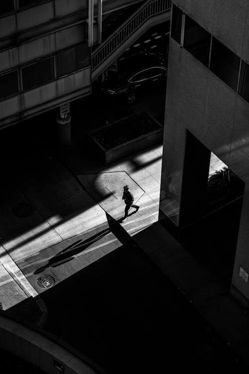Фотография человека, идущего по улице возле зданий в оттенках серого