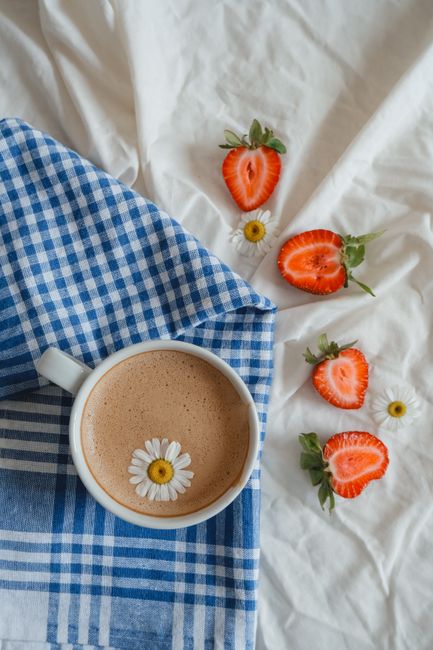 Coffee with chamomile and strawberries on a blue checkered napkin, a cozy still life.