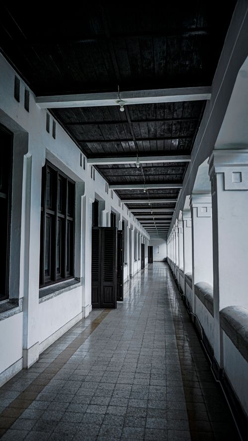 Free Long perspective view of a symmetrical corridor with open doors in an urban building. Ideal for architectural themes. Stock Photo