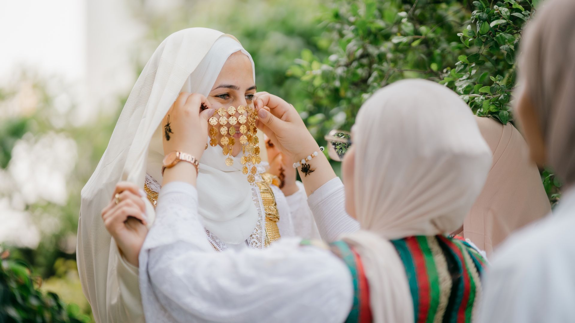 Tunisian bride preparing for wedding with traditional jewelry outdoors.