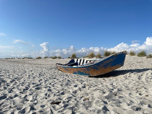 A Wooden Boat on a Beach under Blue Sky 