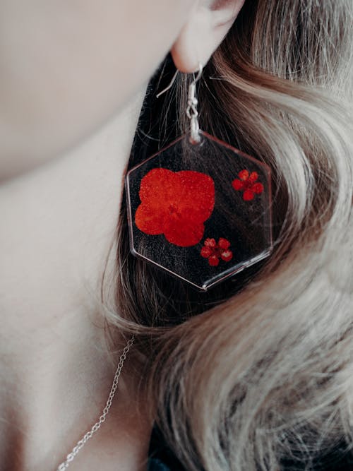 Stylish resin earring on women's ear with embedded red floral design