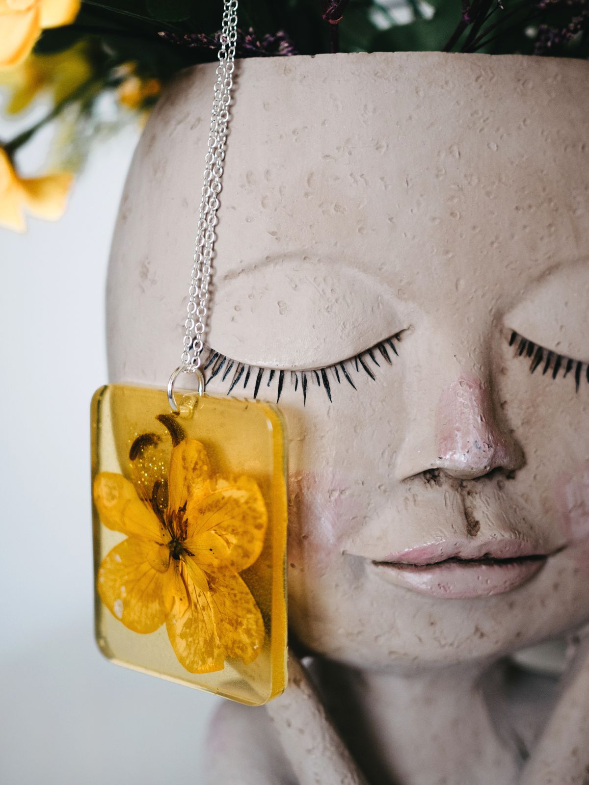 Pendentif en résine avec une fleur jaune.