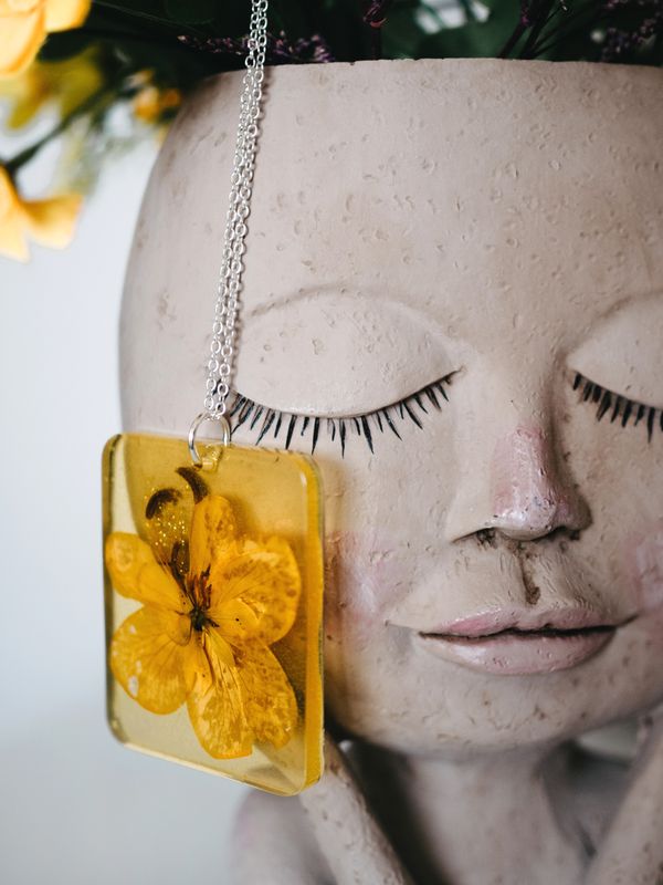 Handmade resin necklace set with a pressed yellow flower — photo by Lisa from Pexels