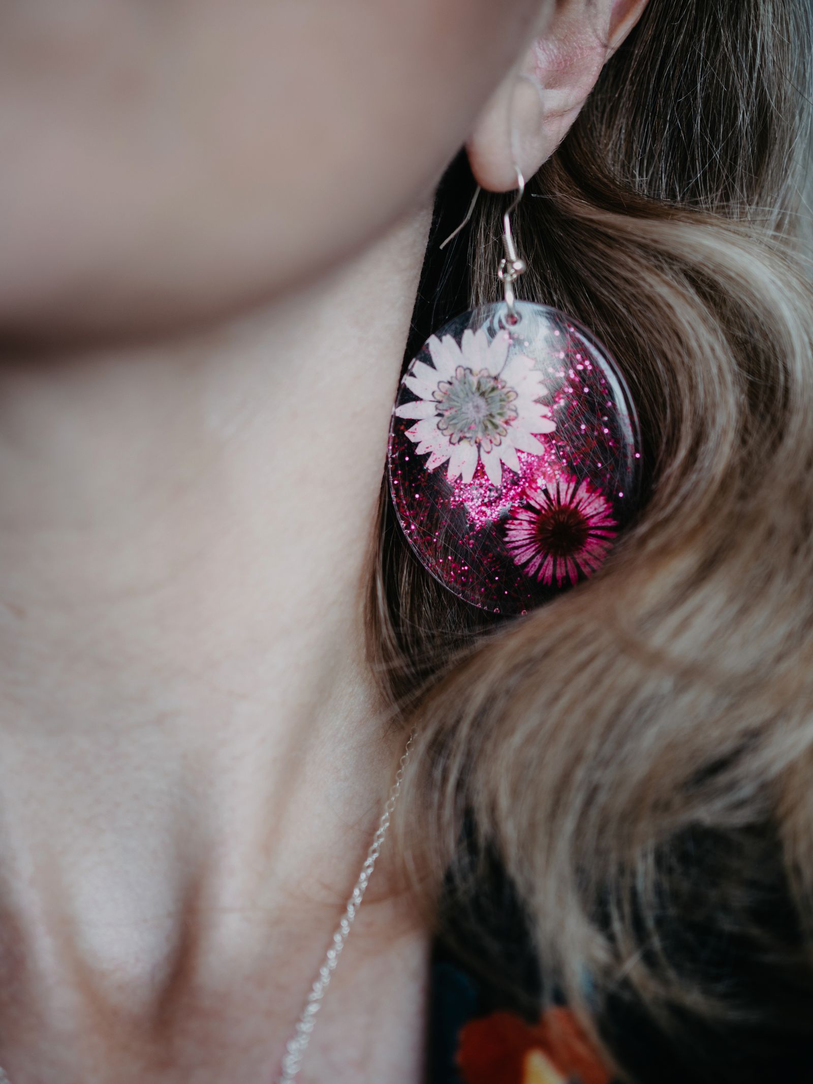 Boucle d'oreille en résine avec fleur séchée.