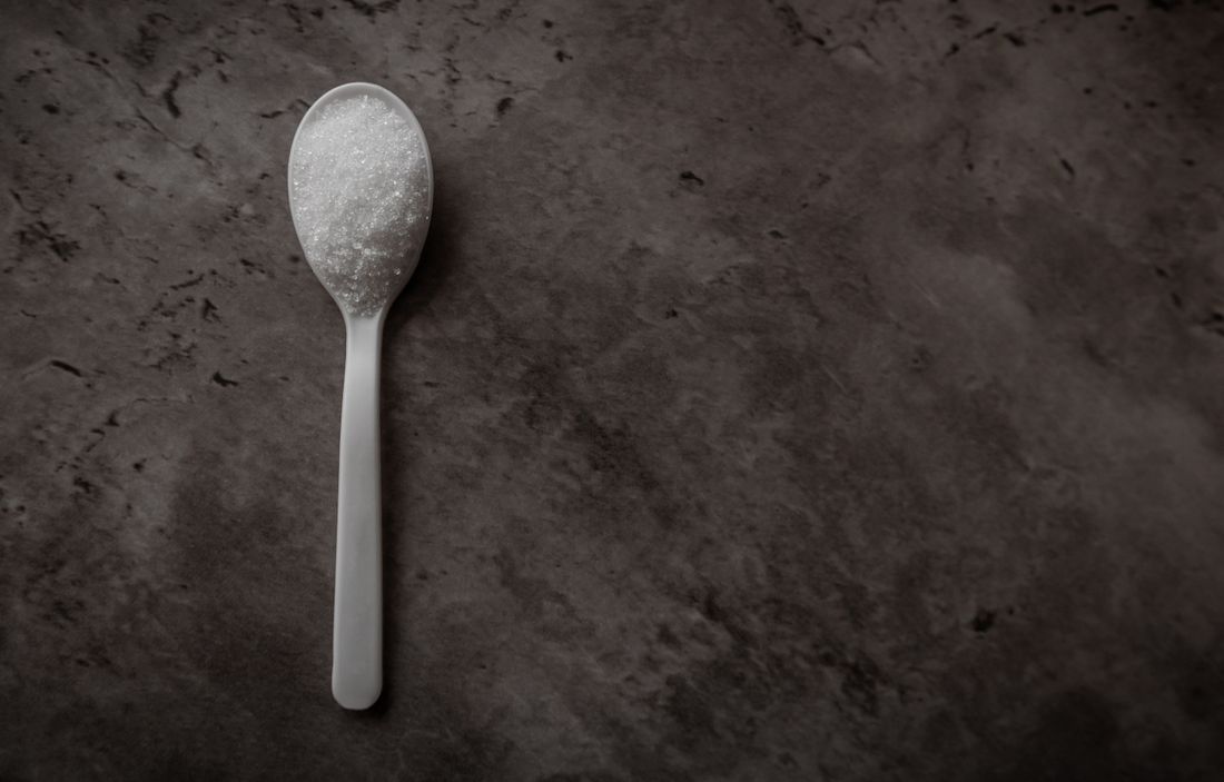 Macro of pure white creatine monohydrate powder on a dark surface